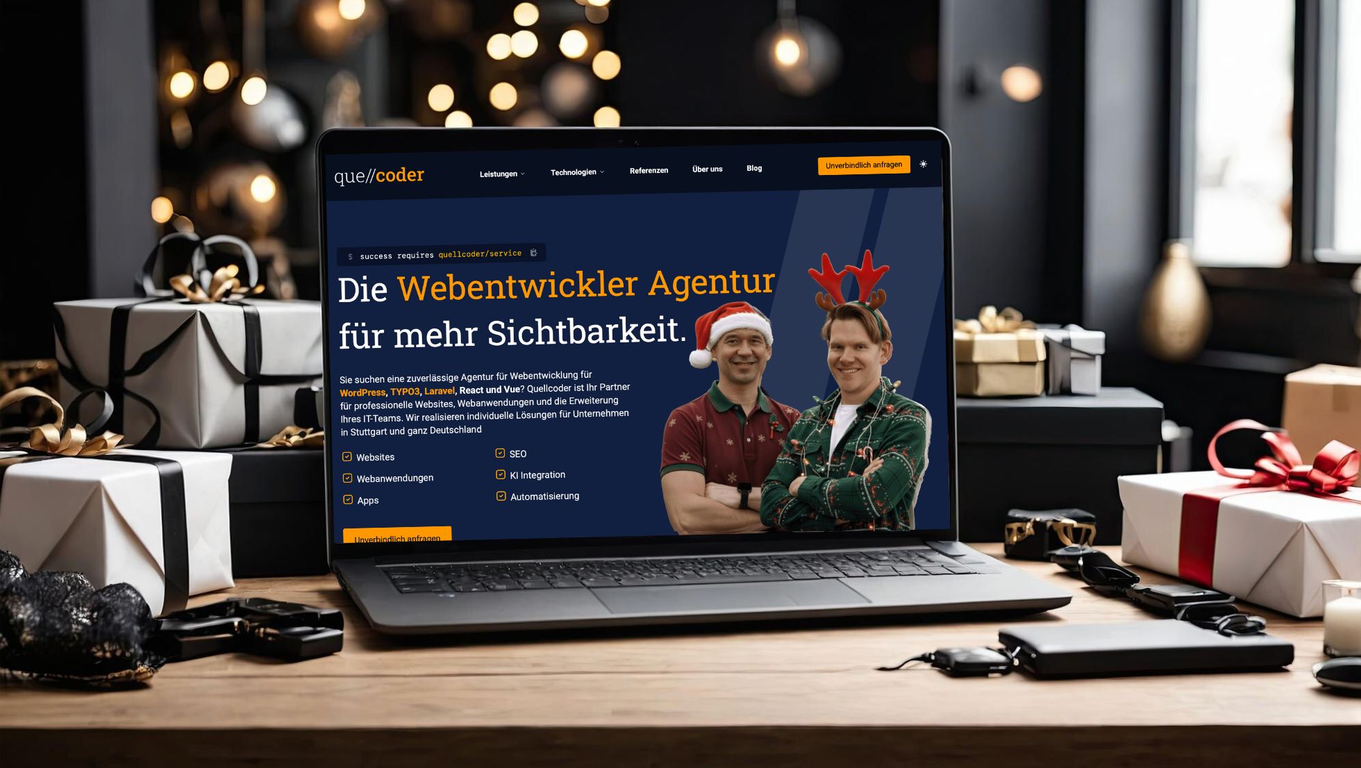 Ein aufgeklappter Laptop zeigt die Website der Webentwickler-Agentur "quellcoder" mit der Überschrift "Die Webentwickler Agentur für mehr Sichtbarkeit" und einem Foto von den beiden Geschäftsführern mit Weihnachtsmützen. Der Laptop steht auf einem Holztisch, umgeben von Weihnachtsgeschenken und unscharfen Lichtern im Hintergrund.