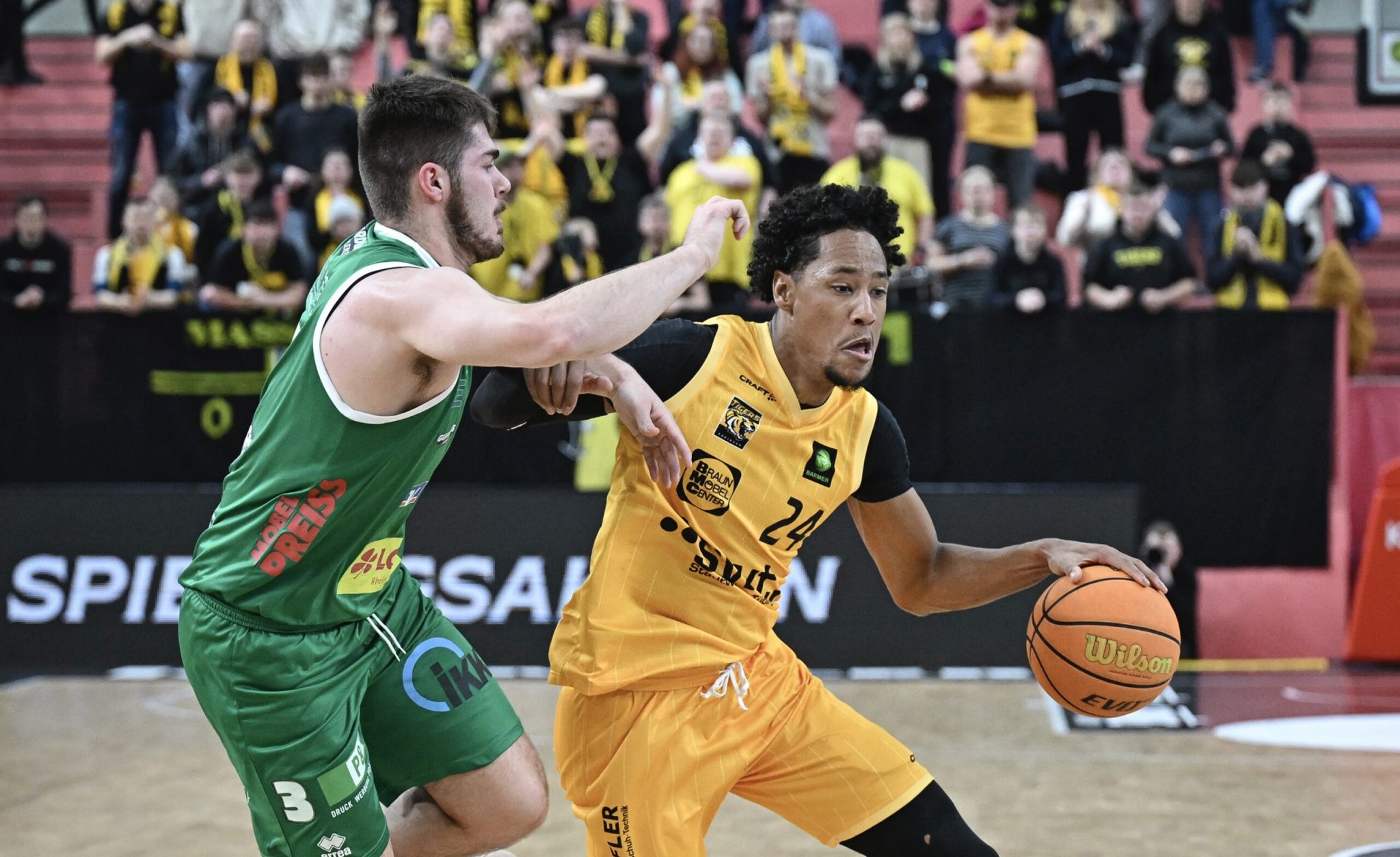 Basketballspieler in Aktion bei einem Vereinsspiel vor Publikum